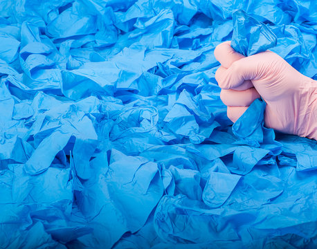 Hand In New Pink Latex Medical Glove On Background Of A Lot Blue Rubber Gloves