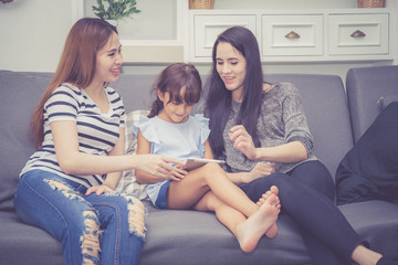 Mother, Aunt and kid having time together lerning with using tablet at home with relax and happy on...