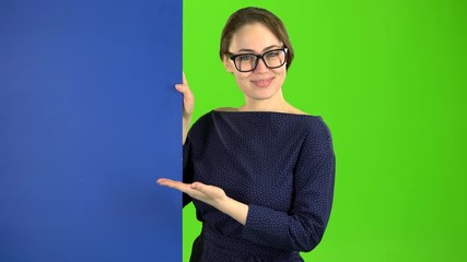 Girl peeks out and points at the billboard. Green screen - Powered by Adobe