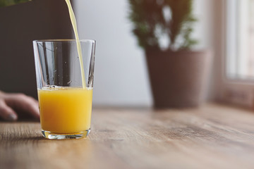 A glass of juice from the morning, she pours the juice of orange juice into a glass