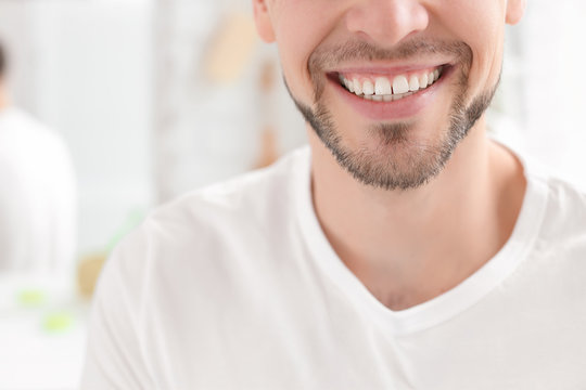 Young man with beautiful smile indoors. Teeth whitening