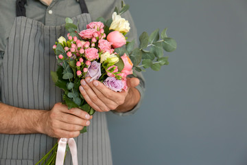 Male florist with beautiful bouquet on color background