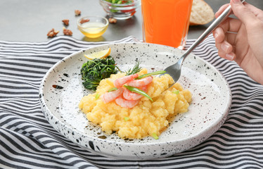 Woman eating fresh tasty shrimp and grits at table