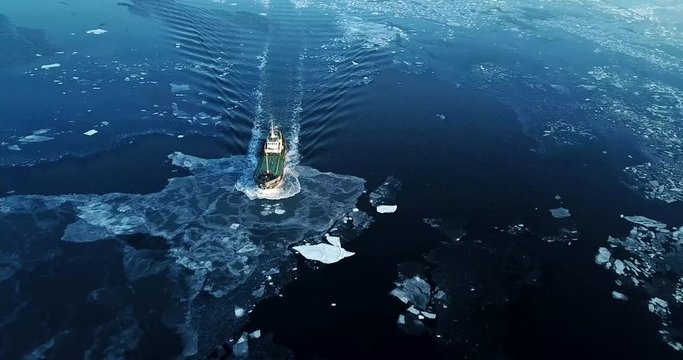 Flying above the Eastern Bosphorus strait. Aerial view of the ship slowly moving through ice floes. Others are stuck on the background. Vladivostok, Russia. Evening