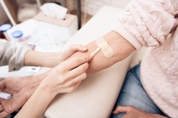 Close up. Girl is nursing elderly woman at home. Girl is helping woman with drop counter.