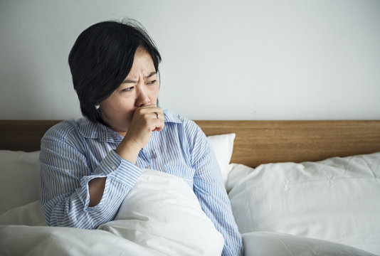 A woman coughing on the bed
