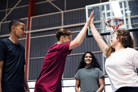 Group of teenager friends on a basketball court giving each other a high five