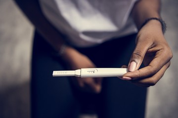 Closeup of black woman with pregnancy test in a hand - obrazy, fototapety, plakaty