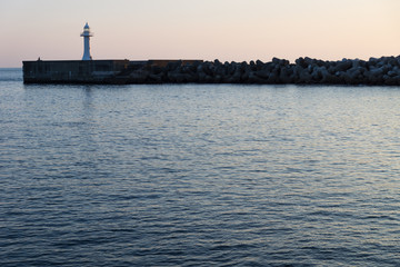 Fisherman at the seawall with lighthouse with wavebreakers in Seogwipo, Jeju Island, South Korea