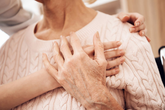 Close up. Girl is caring for elderly woman at home. Girl is embracing woman.