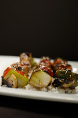 japanese brochette in black background and white plate