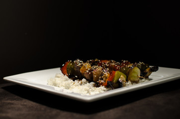 japanese brochette in black background and white plate