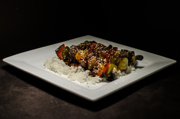 japanese brochette in black background and white plate