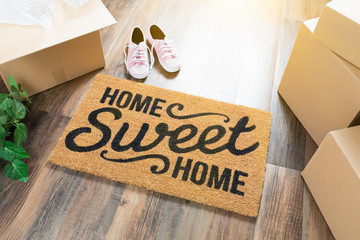 Home Sweet Home Welcome Mat, Moving Boxes, Pink Shoes and Plant on Hard Wood Floors