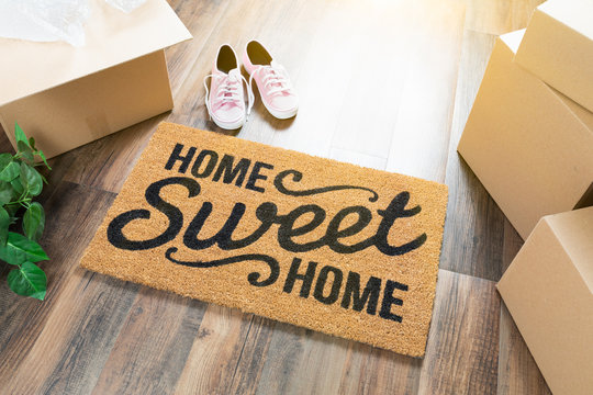 Home Sweet Home Welcome Mat, Moving Boxes, Pink Shoes and Plant on Hard Wood Floors