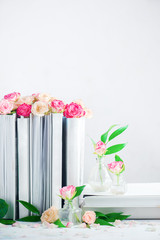 Leisure and reading concept on a white background with copy space. Stack of white books with rose flowers and petals