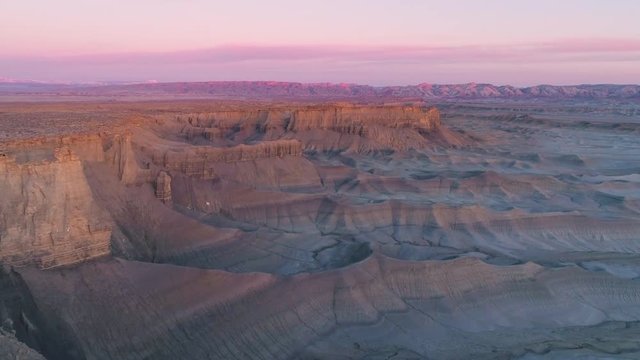 Aerial view flying along colorful cliffs at sunrise in the desert near Factory Butte Caineville, Utah.