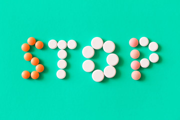Pills on turquoise background . In the form of words stop sign .