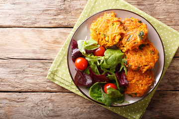 Homemade fritters of sweet potatoes and fresh mix of salad on a plate macro. Horizontal top view