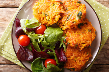 Freshly made crispy fritters from sweet potato and fresh vegetable salad close-up. horizontal top view