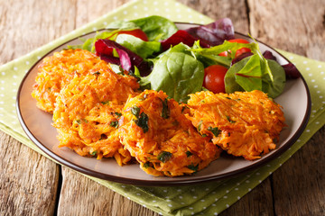 Serving vegetarian crispy pancakes with sweet potato and fresh vegetable salad close-up. horizontal