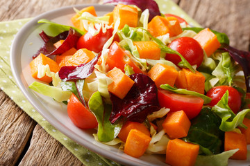 Multicolored salad with baked sweet potato, vegetables and herbs dressed with olive oil close-up. horizontal