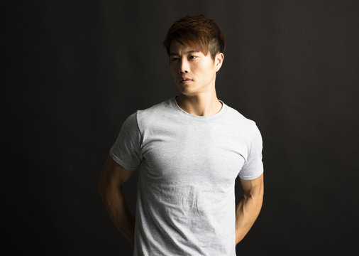 Portrait of young man standing in front of black background.