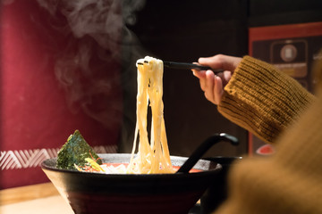 noodle ramen on chopstick hold on women hand, food and drink concpet with copy space