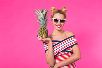 Fashion summer portrait woman with sunglasses and pineapple over pink background