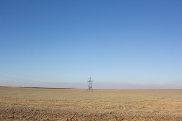 Desert steppe with a power tower in the middle of the field.
