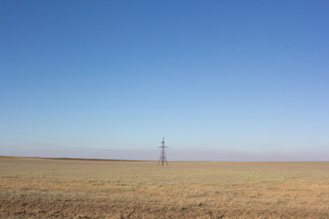 Desert steppe with a power tower in the middle of the field.