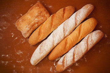 Assortment of baked bread on wooden background. Top view.
