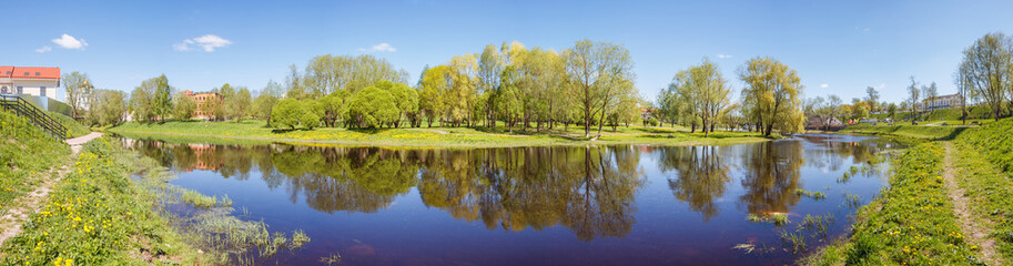 Trees of the park with reflection in the river in Pskov