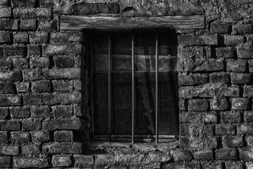 Old brick wall with brick filled window with grid.