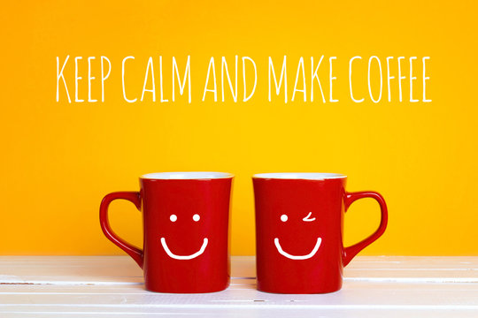 Two red coffee mugs with a smiling faces on a yellow background with the phrase Keep calm and make coffee.
