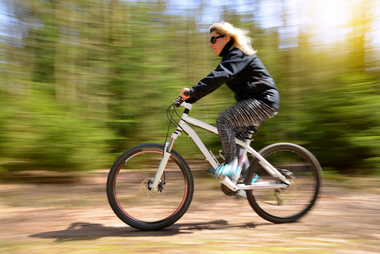 Woman riding a mountain bike on a forest path. Sport and active life concept. Motion blurred shot.