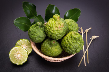 Obraz premium Bergamot, kaffir lime and kaffir lime leaf with basket on dark background