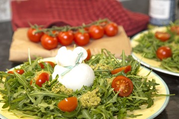 Italian burrata cheese with arugula, pesto sauce and cherry tomatoes on a  plate