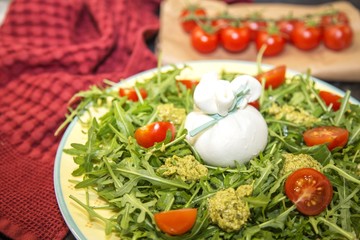 Italian burrata cheese with arugula, pesto sauce and cherry tomatoes . Tasty food