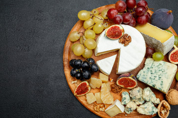 Brie cheese on a wooden Board with fresh figs and grapes