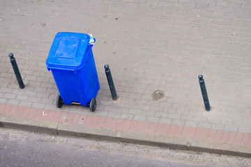 Blue trash can on street pavement