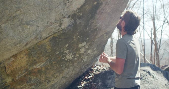 Climber Looks Up at boulder While he chalks his hands 4K