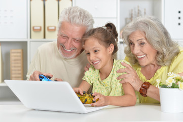 Grandparents with her granddaughter playing computer games with 