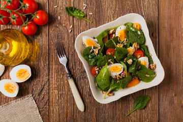 Delicious salad of fresh spinach, boiled egg, tomatoes, nuts and sunflower seeds