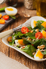 Delicious salad of fresh spinach, boiled egg, tomatoes, nuts and sunflower seeds