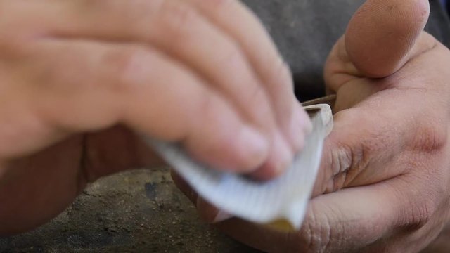 Woodworker smooths the edges of wooden sunglasses by hand. Close up.