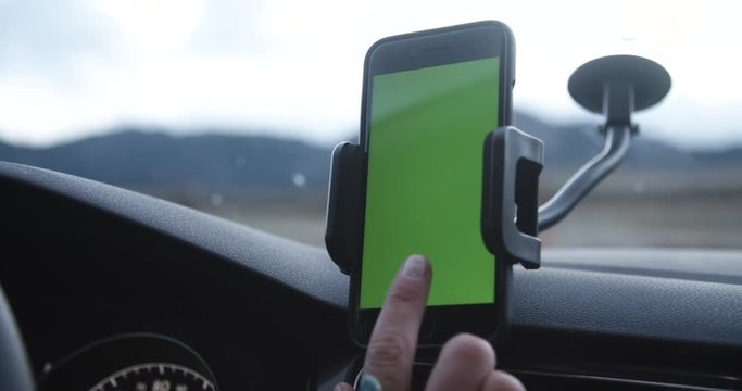 Female rideshare driver starts trip on phone app with car mount