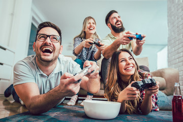 Group of friends play video games together at home, having fun.