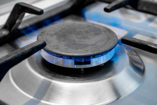 The gas burns in the burner of a kitchen stove 