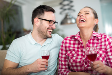 Photo of a young cheerful couple toasting at home with wine.